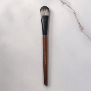 Makeup brush with wooden handle and black ferrule on a light gray background