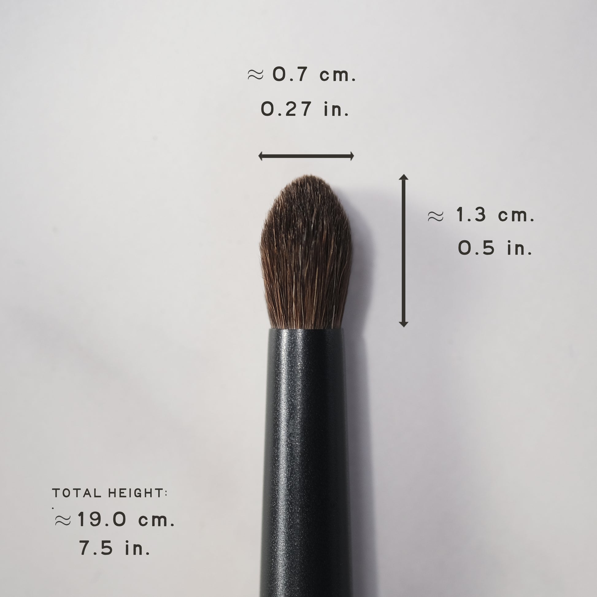 Makeup brush with measurements on a light gray background