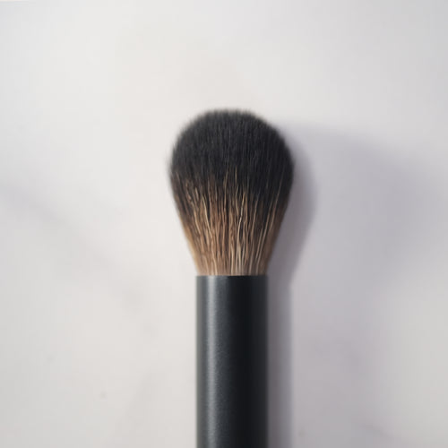 Makeup brush with black handle and bristles on a light gray background