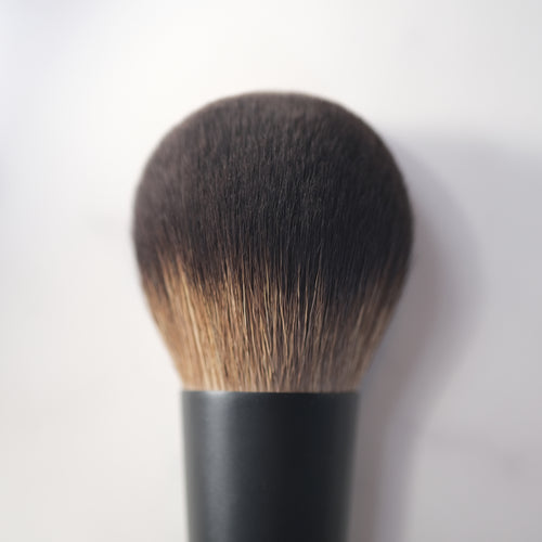 Makeup brush with black handle and brown bristles on a white background
