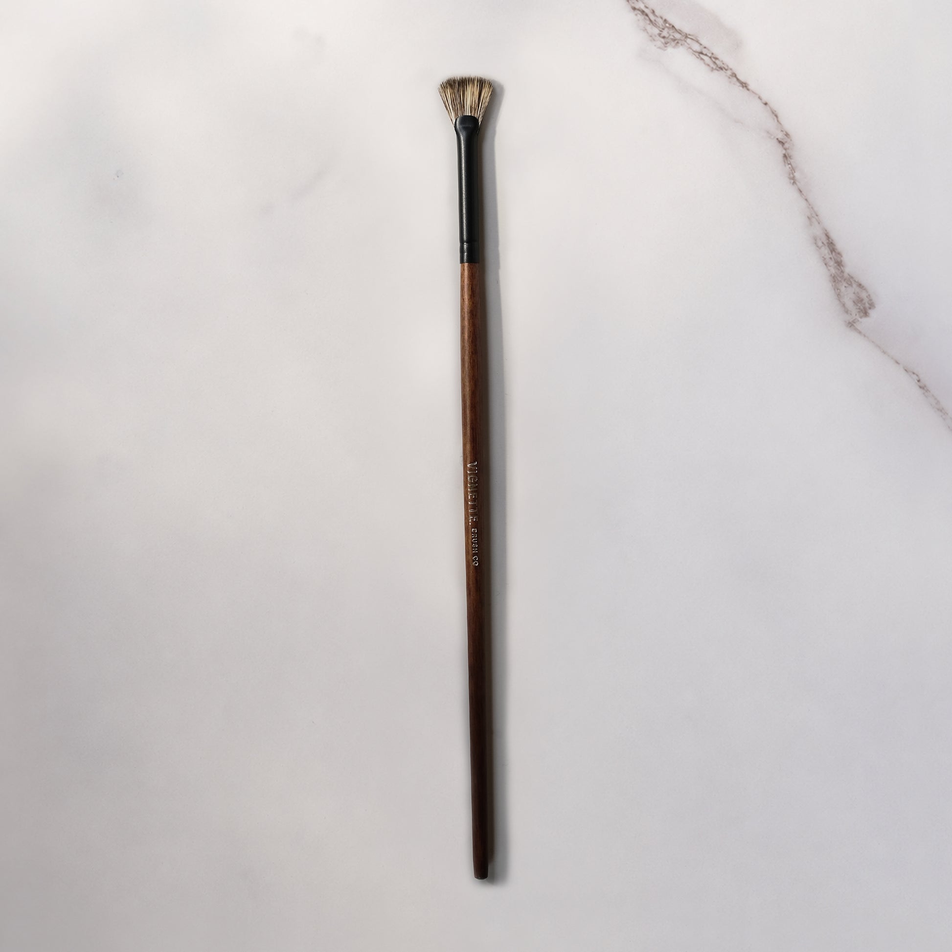 Makeup brush with wooden handle on a light gray background