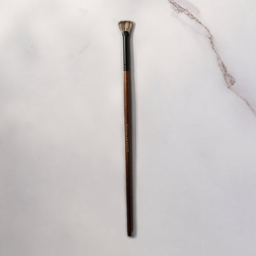 Makeup brush with wooden handle on a light gray background