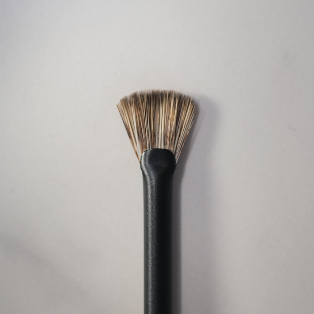 Black makeup brush with bristle head on a gray background