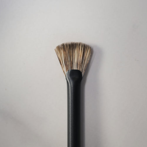 Black makeup brush with bristle head on a gray background