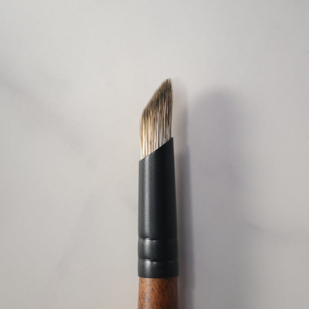 Makeup brush with wooden handle and black ferrule on a light gray background