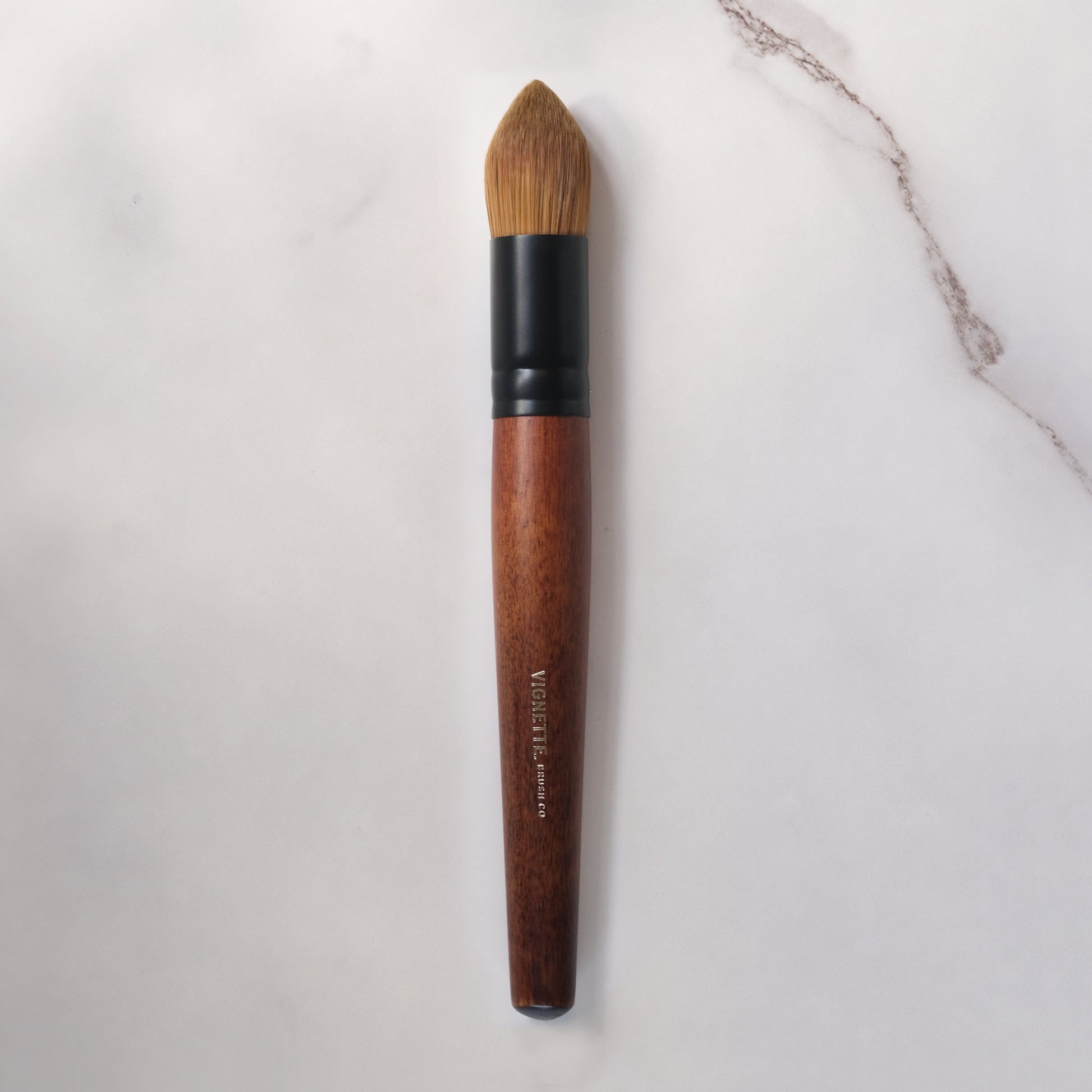 Makeup brush with wooden handle and black ferrule on a light gray background
