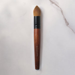 Makeup brush with wooden handle and black ferrule on a light gray background