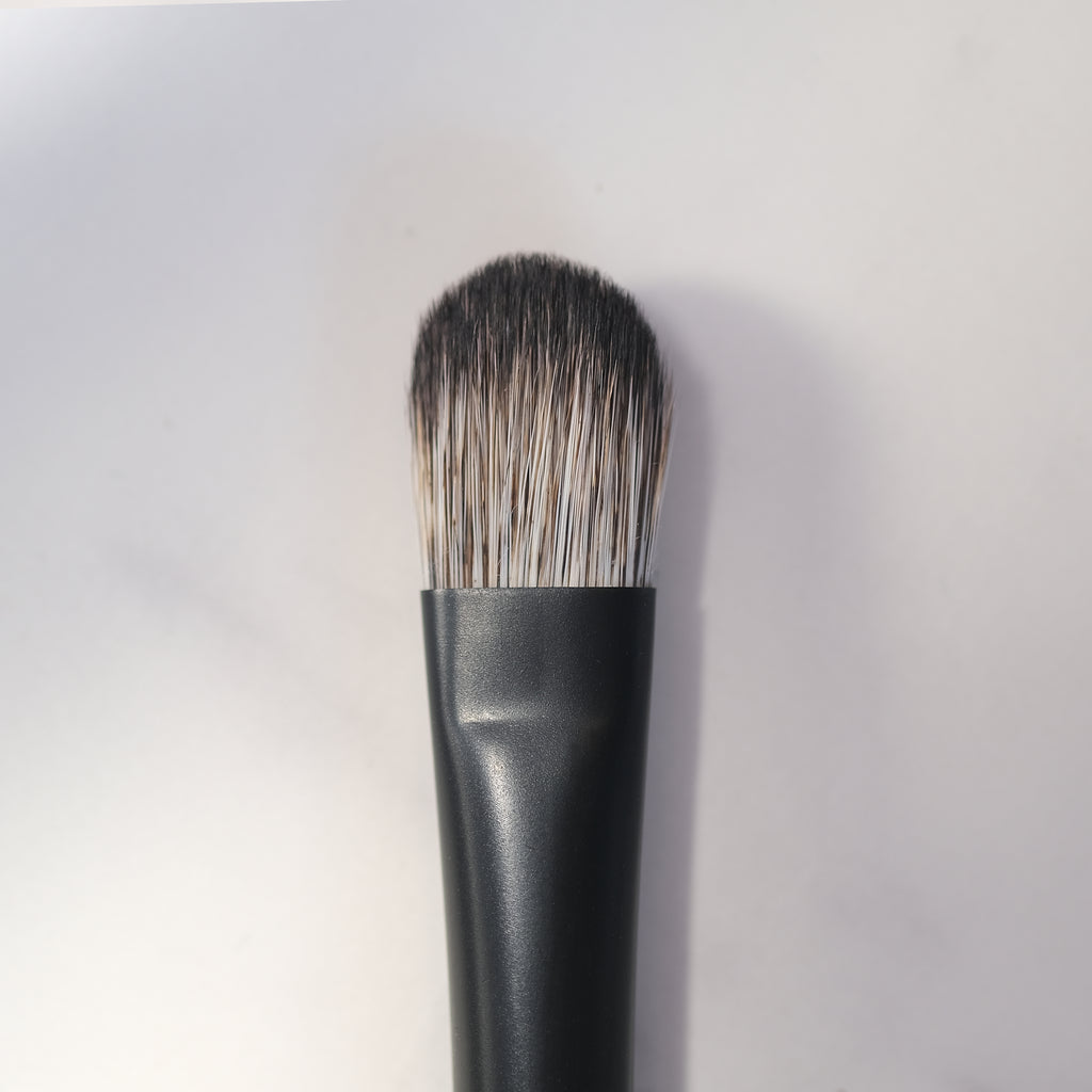 Makeup brush with black handle and bristles on a white background