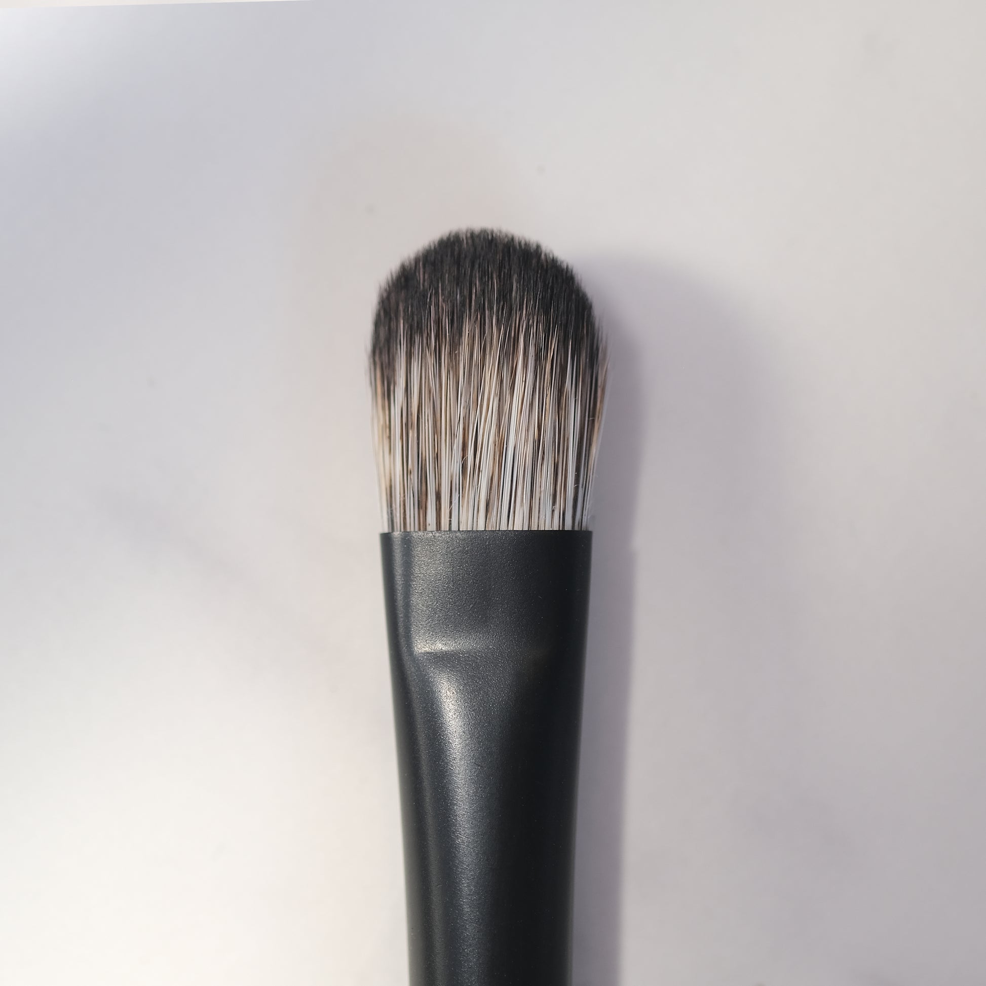 Makeup brush with black handle and bristles on a white background