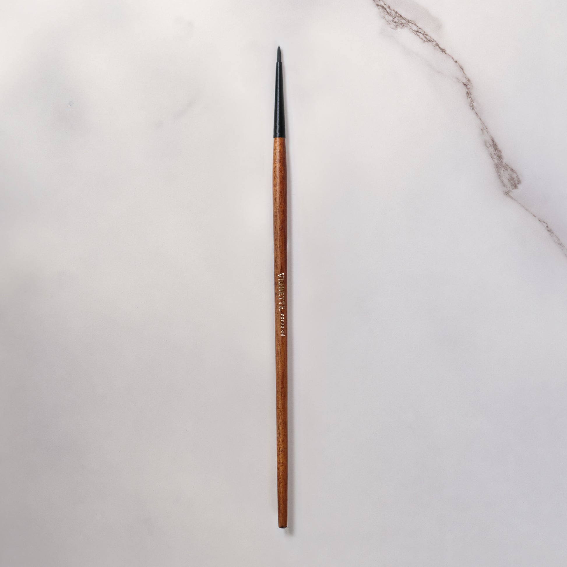 Long wooden pen with black tip on a light gray background