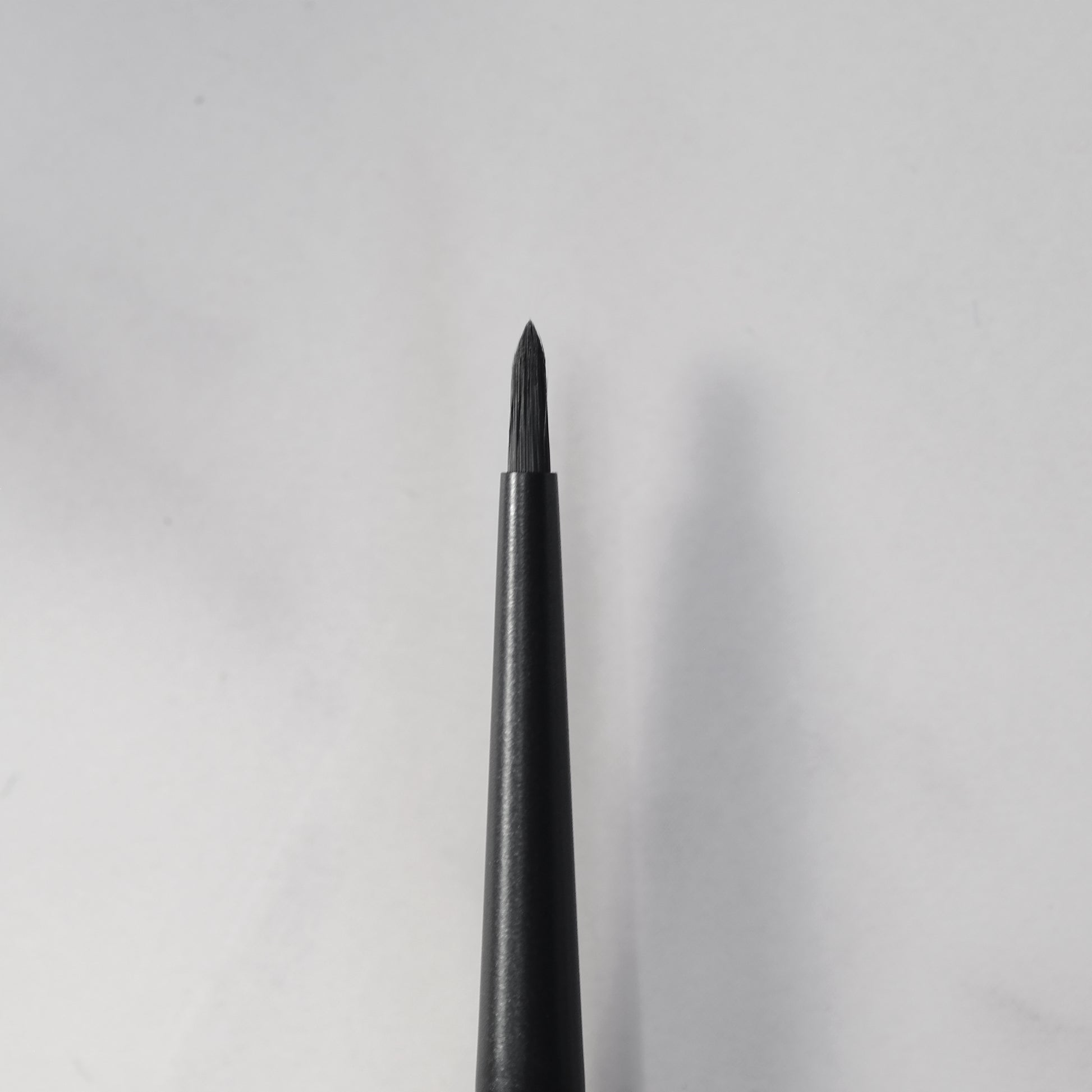 Black eyeliner pencil on a light gray background