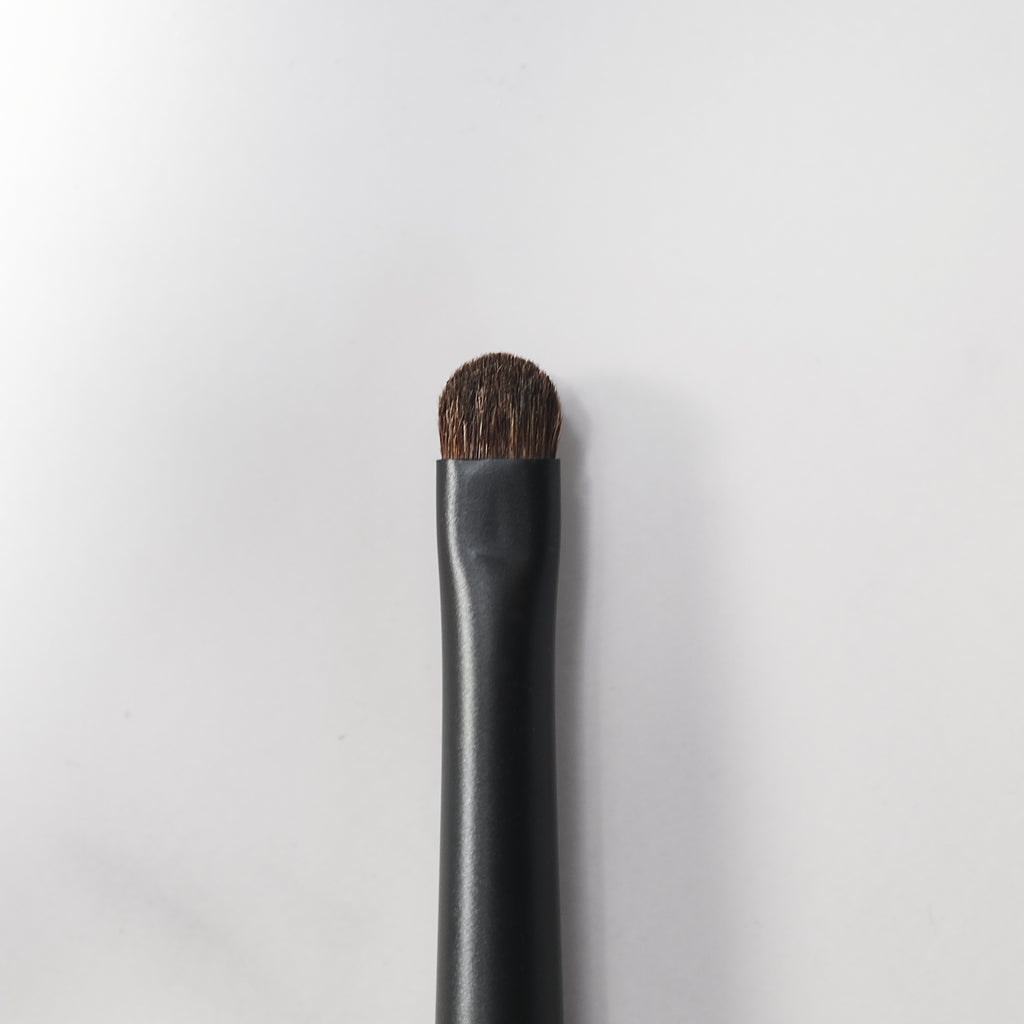 Makeup brush with black handle and brown bristle on a white background