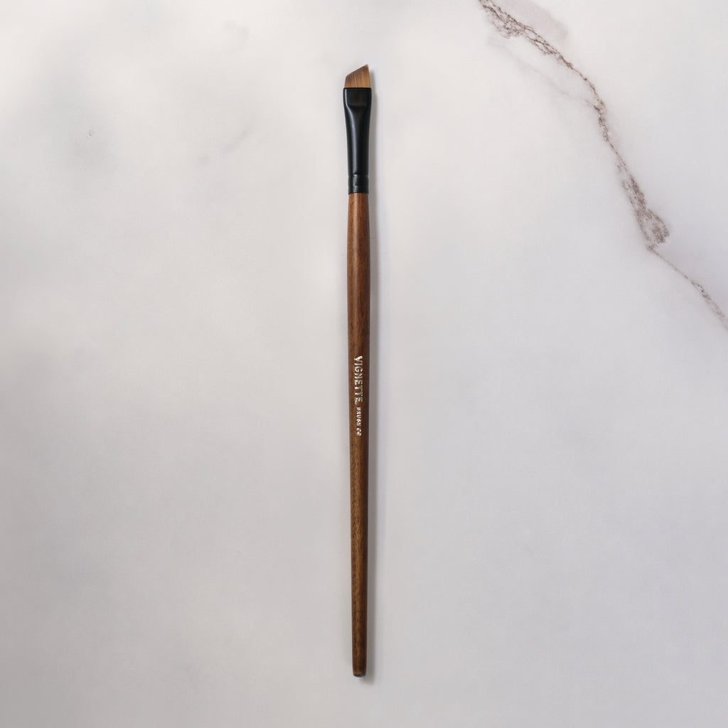 Makeup brush with wooden handle on a light gray background