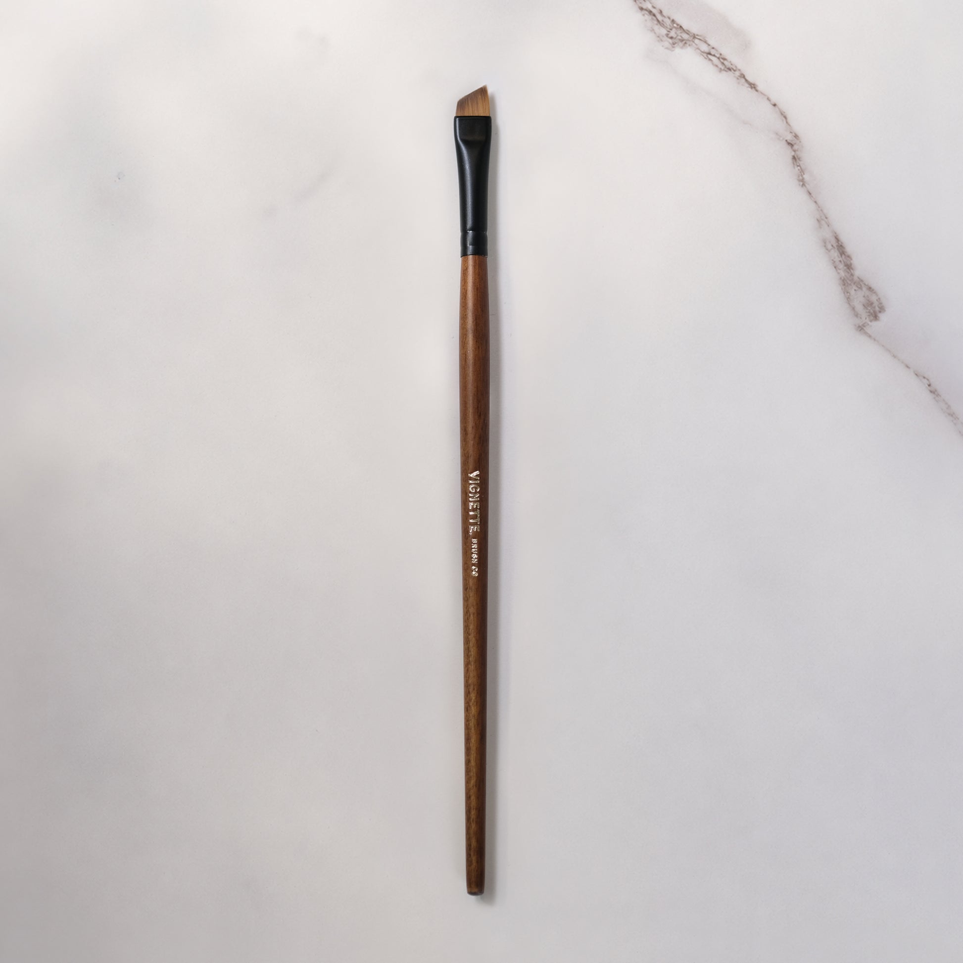 Makeup brush with wooden handle on a light gray background