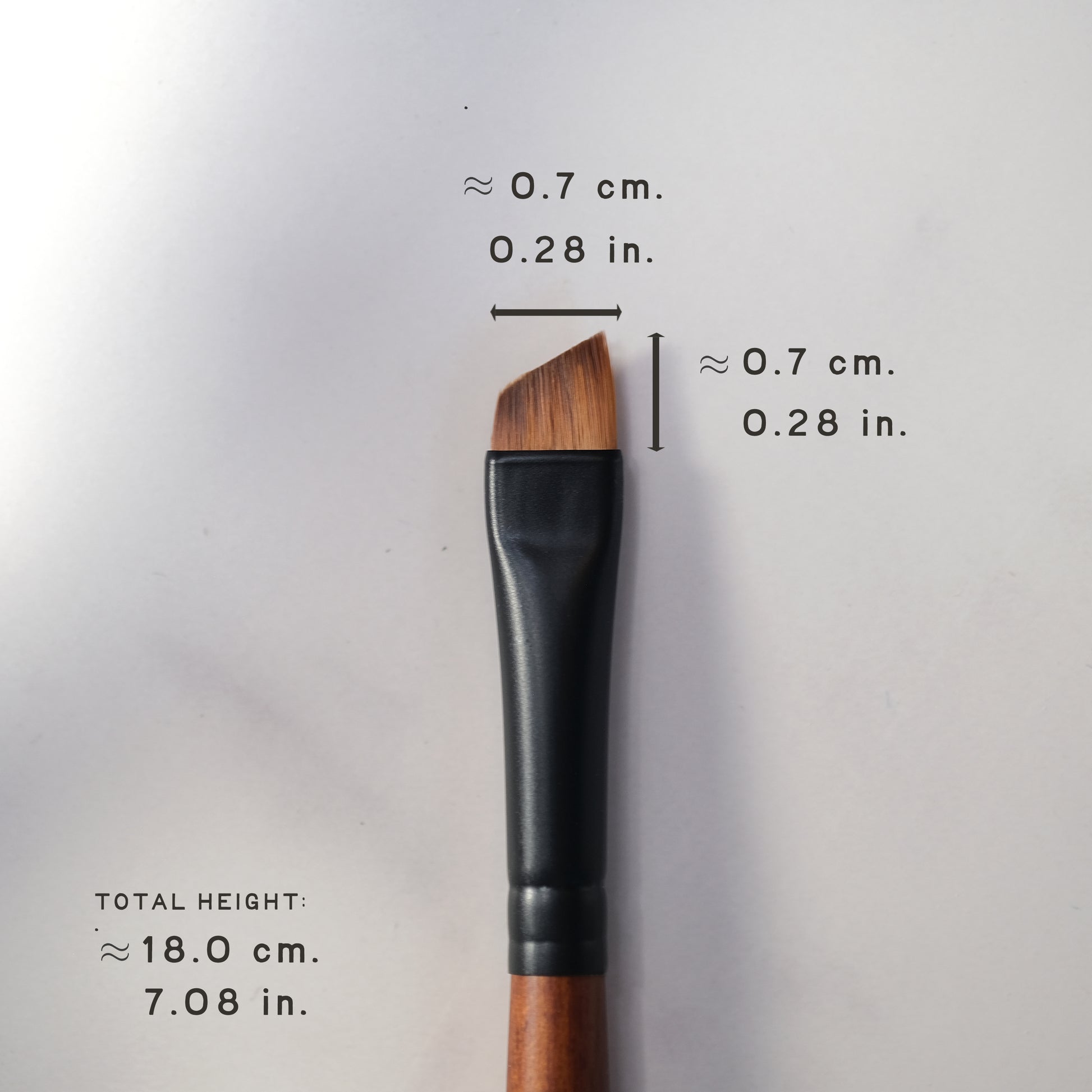Makeup brush with measurements on a light gray background