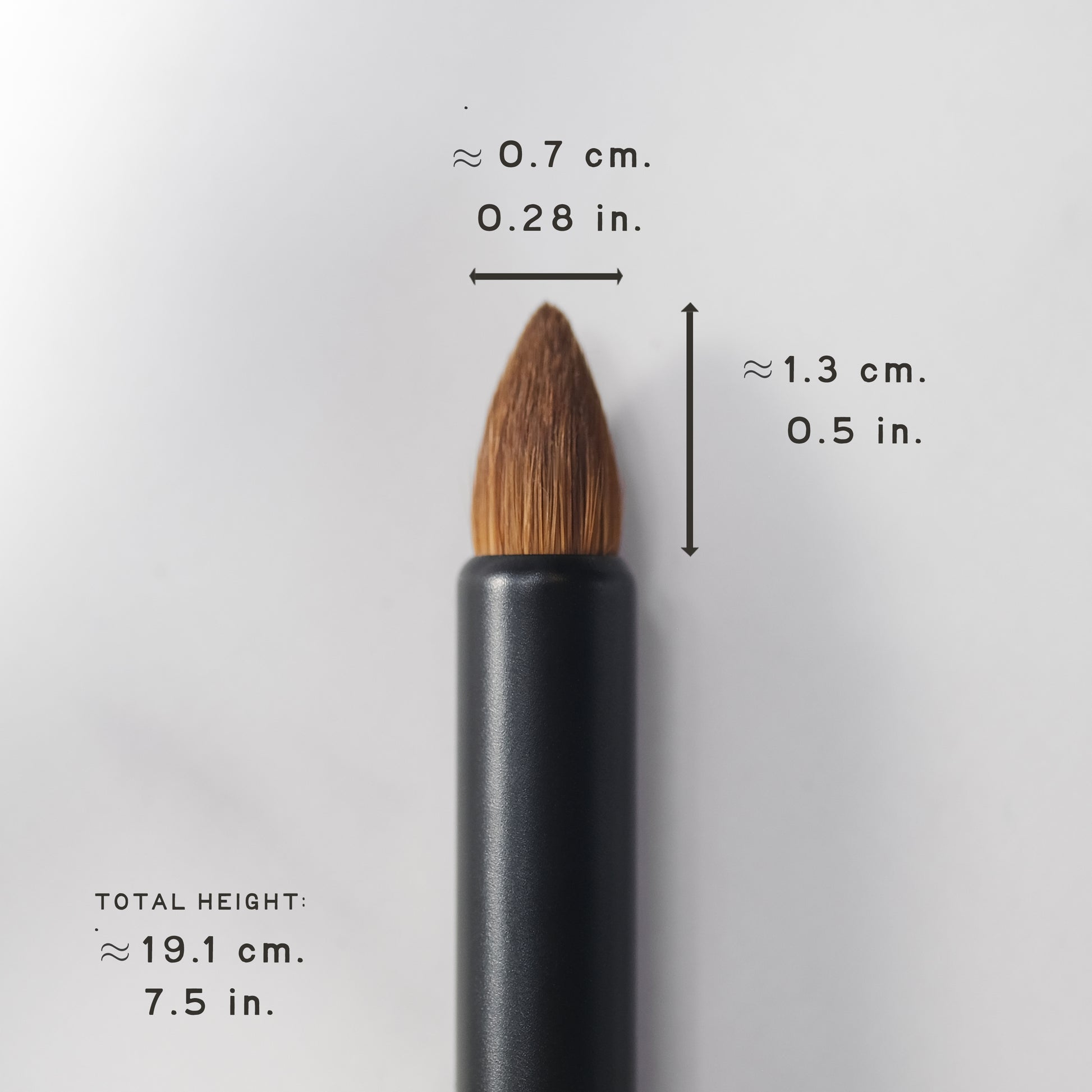 Black makeup brush with measurements on a light gray background
