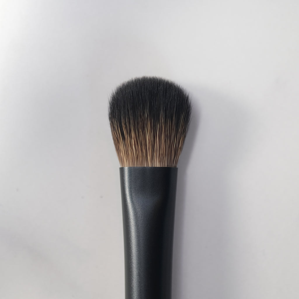 Makeup brush with black handle and bristles on a light gray background
