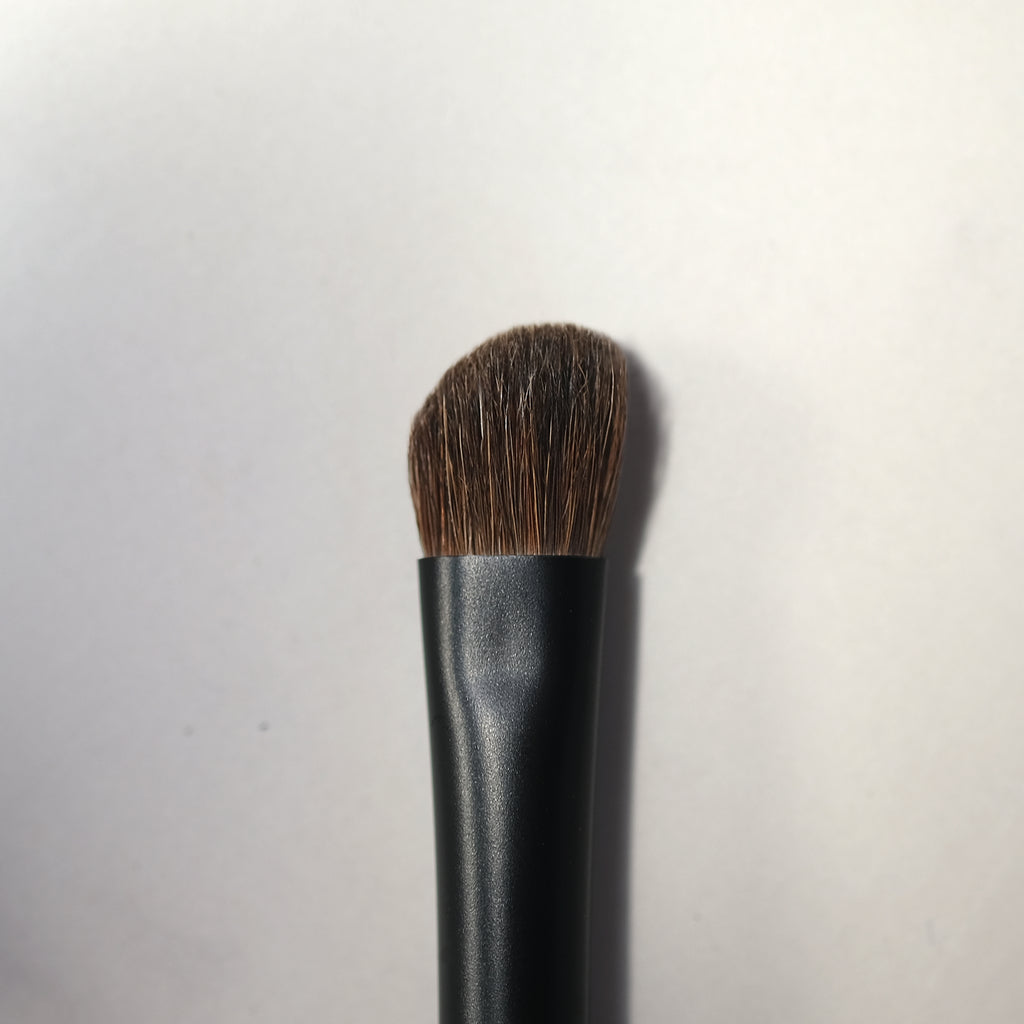 Makeup brush with black handle and brown bristles on a white background