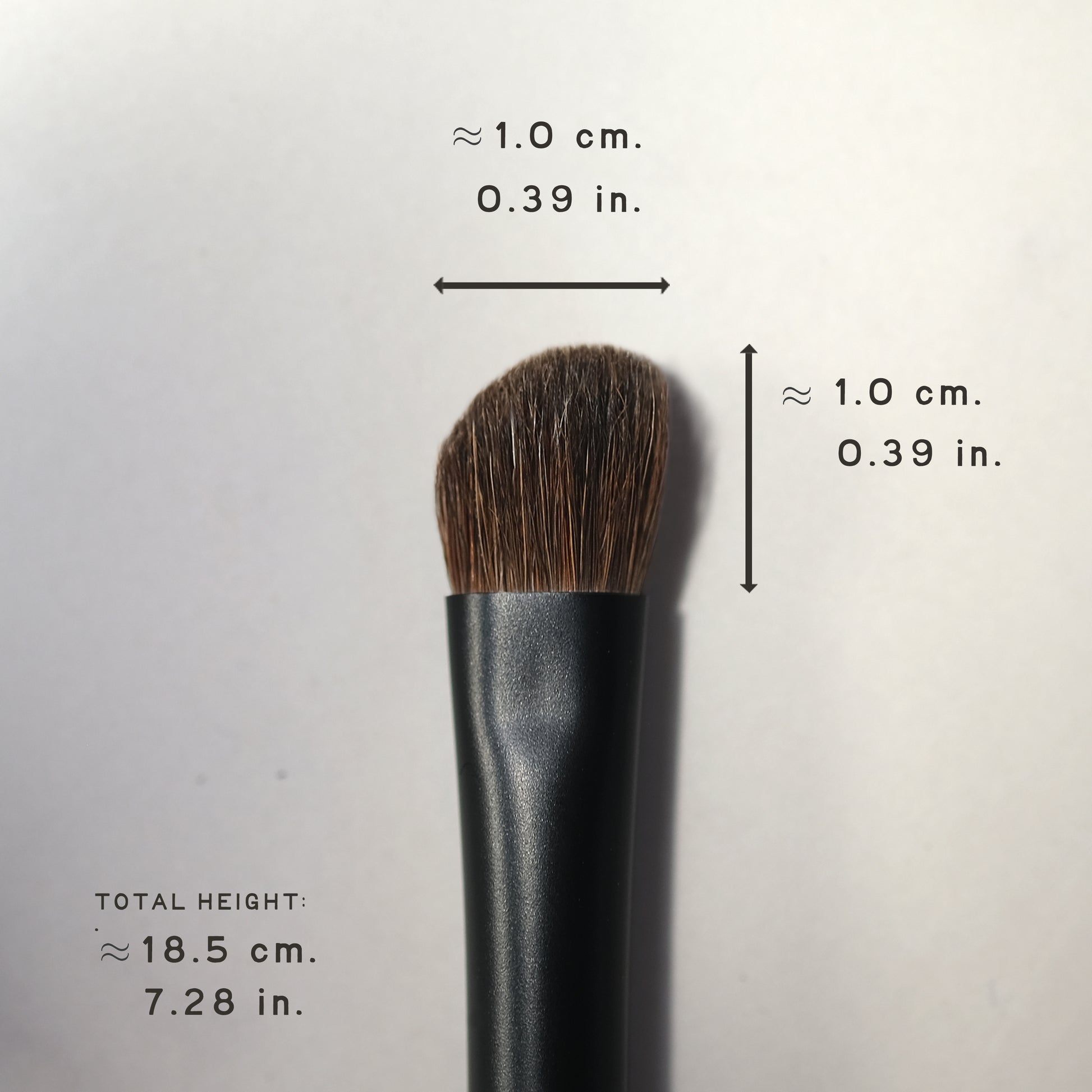 Makeup brush with measurements on a light gray background
