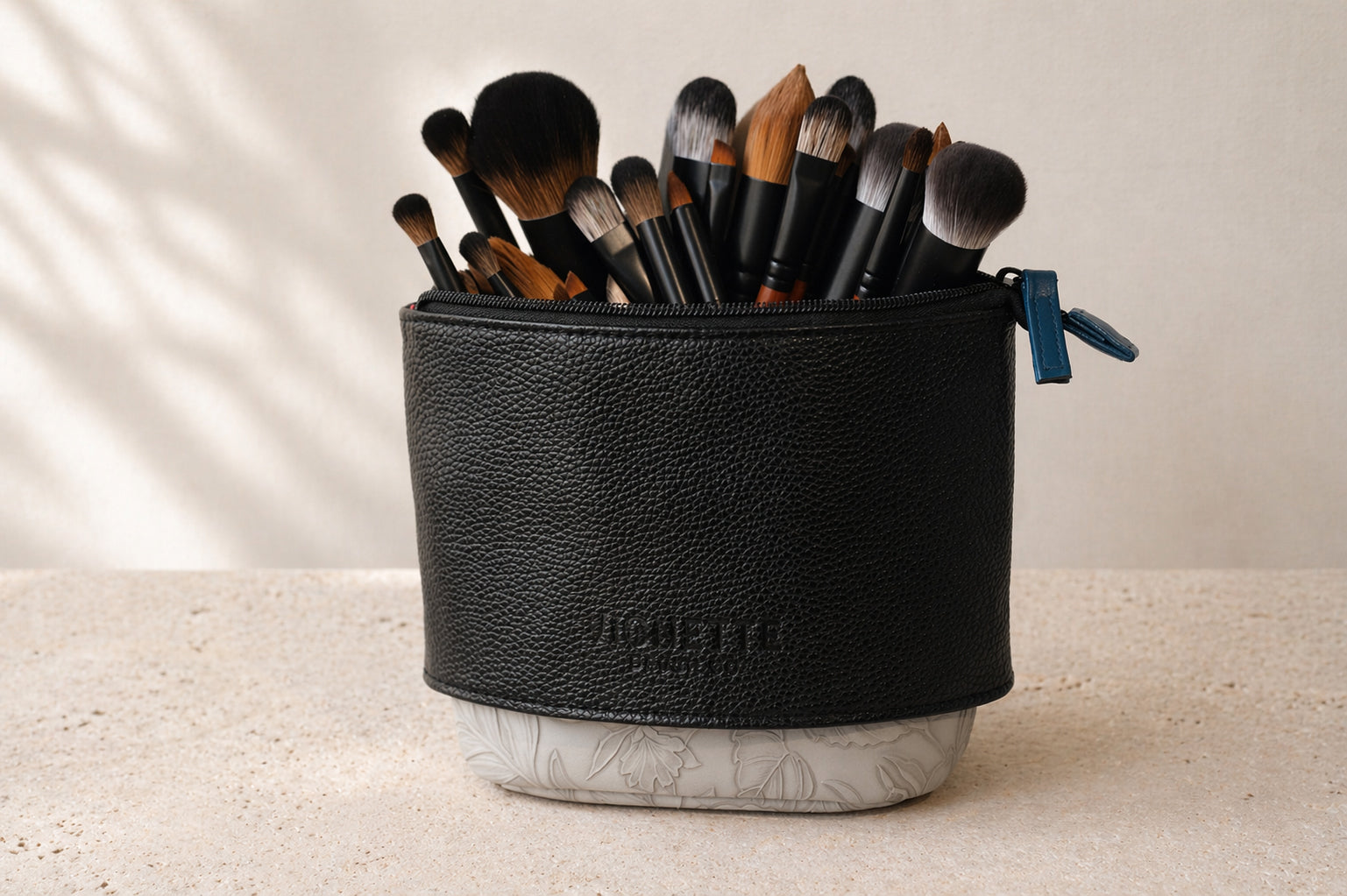 Black makeup brush holder with brushes inside on a light background
