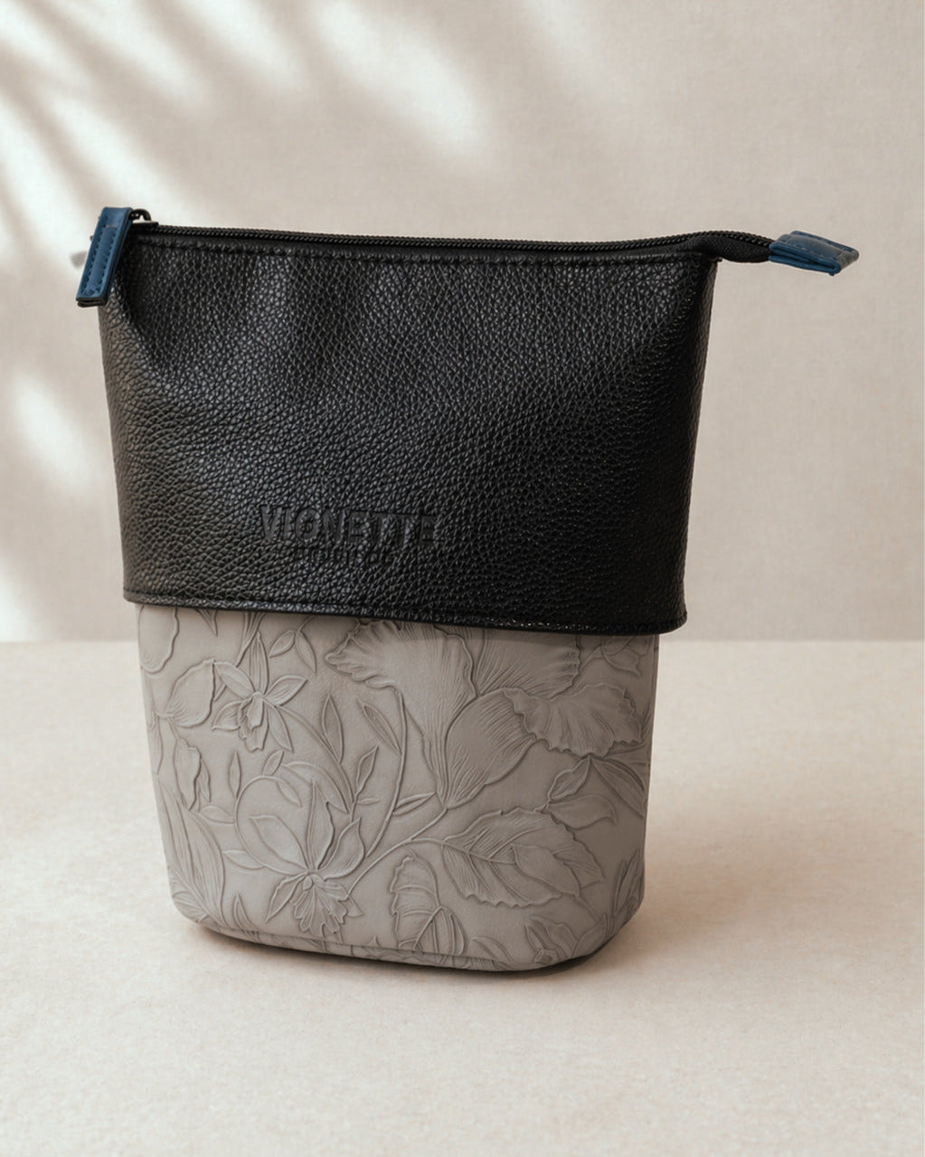 Black and gray pouch with floral pattern on a light background